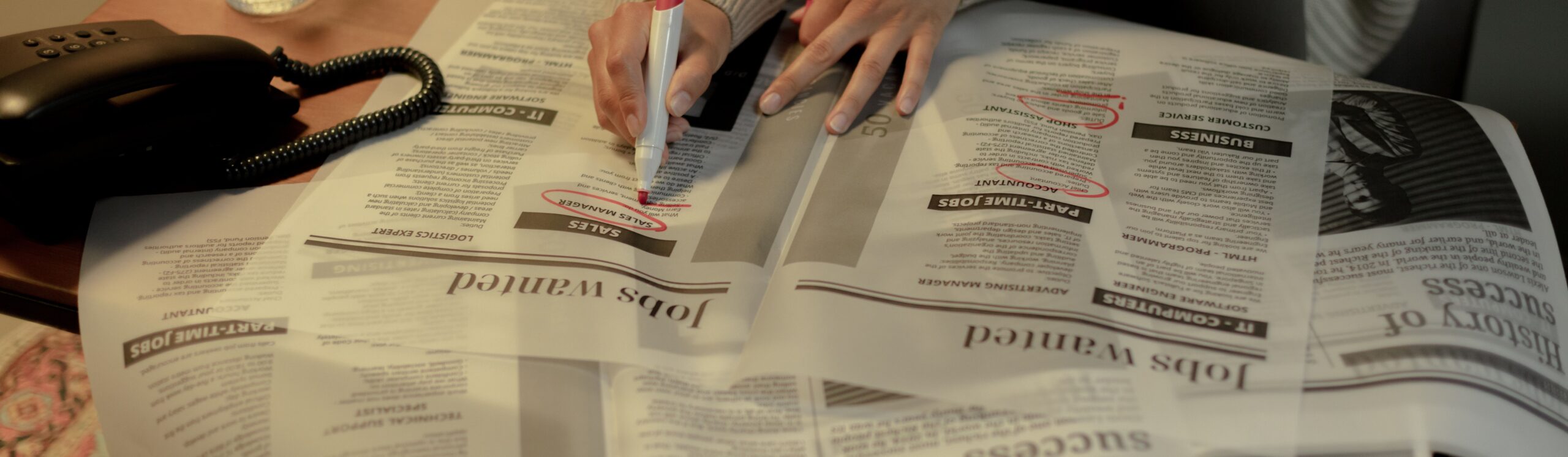 Close up of hand with pen circling job ads.